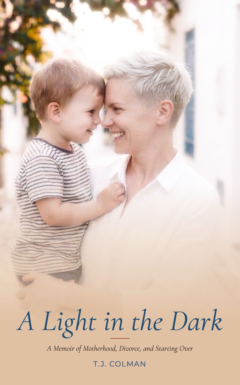 Cover of A Light in the Dark: a smiling woman with short hair holds a young boy close.